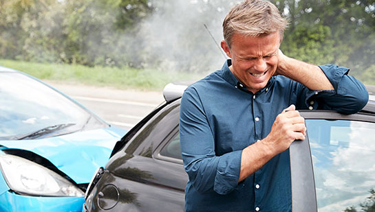 Man with whiplash from auto accident holding his neck in pain before visiting Denver chiropractor